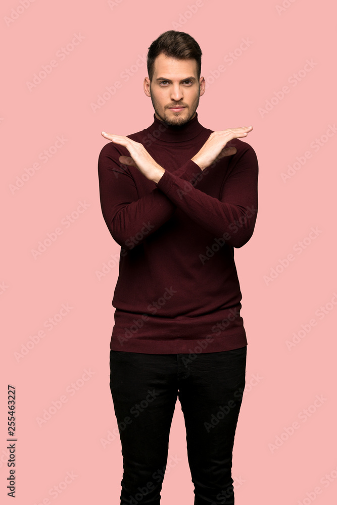 Man with turtleneck sweater making NO gesture over pink background Man with turtleneck sweater making NO gesture over pink background