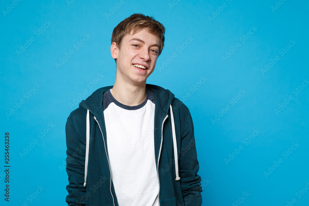 Portrait of smiling cheerful joyful young man in casual clothes standing isolated on blue wall background in studio. People sincere emotions, lifestyle concept. Mock up copy space. Advertising area. Portrait of smiling cheerful joyful young man in casual clothes standing isolated on blue wall background in studio. People sincere emotions, lifestyle concept. Mock up copy space. Advertising area.