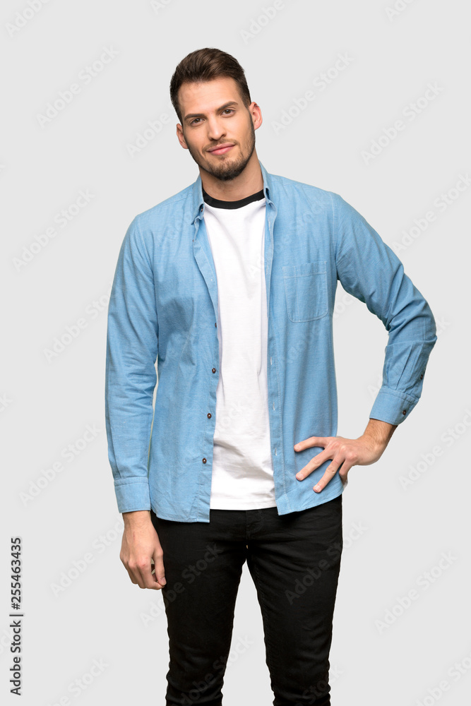 Handsome man posing with arms at hip and smiling over grey background Handsome man posing with arms at hip and smiling over grey background
