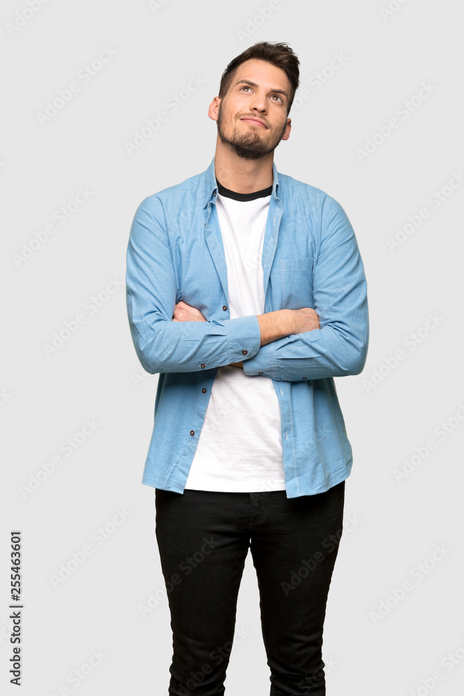 Handsome man looking up while smiling over grey background Handsome man looking up while smiling over grey background