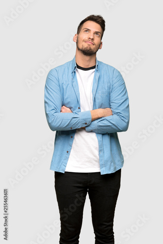 Handsome man looking up while smiling over grey background