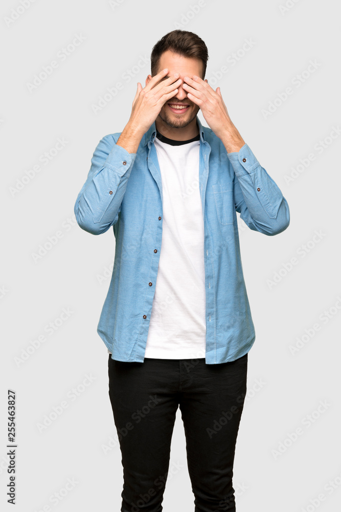 Handsome man covering eyes by hands. Surprised to see what is ahead over grey background Handsome man covering eyes by hands. Surprised to see what is ahead over grey background