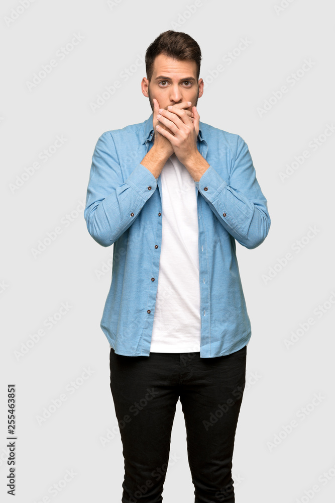 Handsome man covering mouth with hands for saying something inappropriate over grey background Handsome man covering mouth with hands for saying something inappropriate over grey background