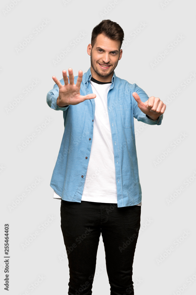 Handsome man counting six with fingers over grey background Handsome man counting six with fingers over grey background