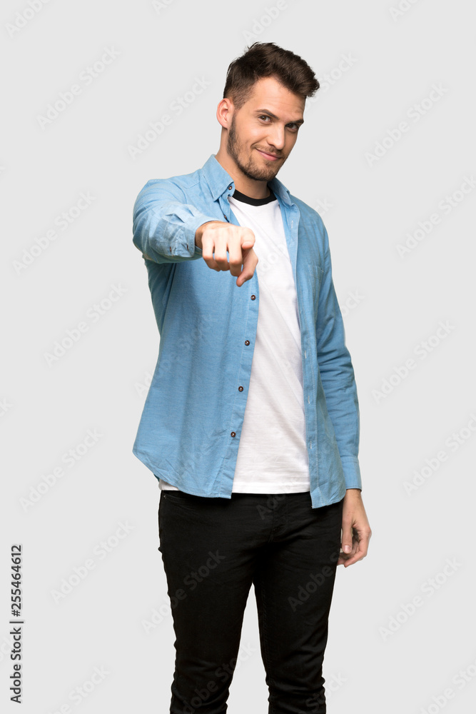 Handsome man points finger at you with a confident expression over grey background Handsome man points finger at you with a confident expression over grey background