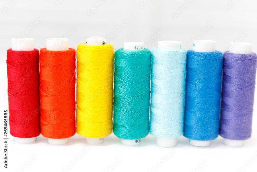 a row of spools of thread. rainbow colors a row of spools of thread. rainbow colors