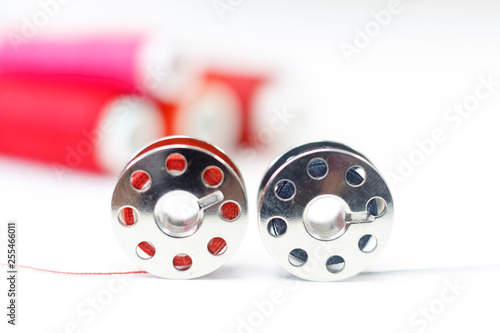 sewing bobbin and row of spools of thread