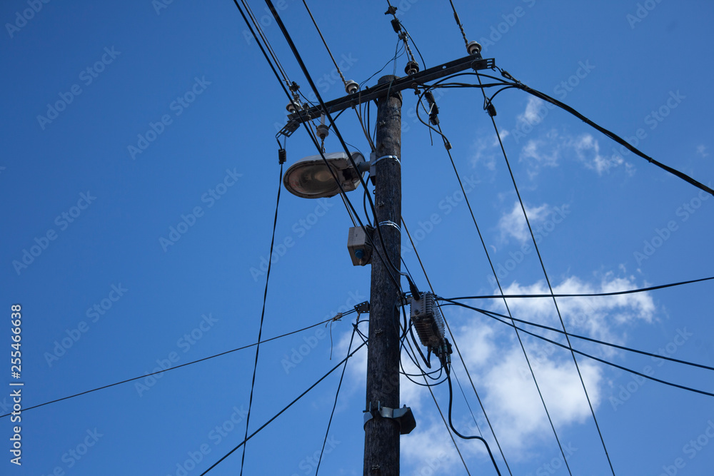 Hölzerne Strommast mit Strassenlaterne und Telekomleitungen Hölzerne Strommast mit Strassenlaterne und Telekomleitungen