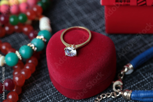 White gold diamond ring on top of colored stones. Romantic background ( Valentine's Day) 