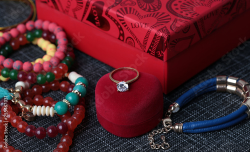White gold diamond ring on top of colored stones. Romantic background ( Valentine's Day) 