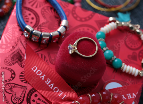 White gold diamond ring on top of colored stones. Romantic background ( Valentine's Day) 