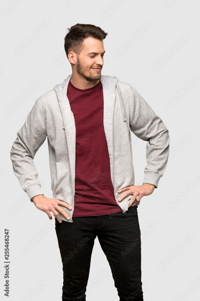 Man with sweatshirt posing with arms at hip and smiling over grey background Man with sweatshirt posing with arms at hip and smiling over grey background
