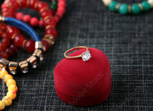 White gold diamond ring on top of colored stones. Romantic background ( Valentine's Day) 