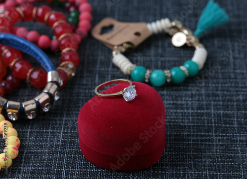 White gold diamond ring on top of colored stones. Romantic background ( Valentine's Day) 