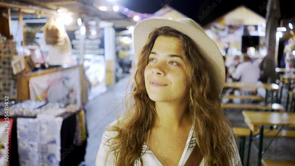 Crop portrait young girl in hat walking through european city market at night in Lisbon Crop portrait young girl in hat walking through european city market at night in Lisbon