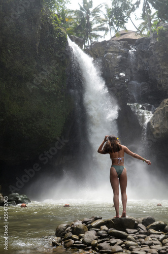 Young beautiful tourist visiting the Tegenungan waterfall in Bali