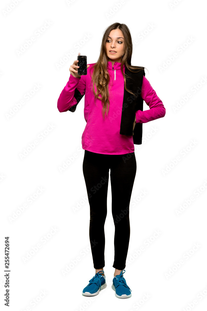 Full-length shot of Young sport woman with troubled holding broken smartphone over isolated white background Full-length shot of Young sport woman with troubled holding broken smartphone over isolated white background