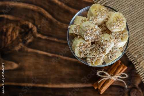 close up on glass jar with pieces of banana with oats, Wooden and jute Background