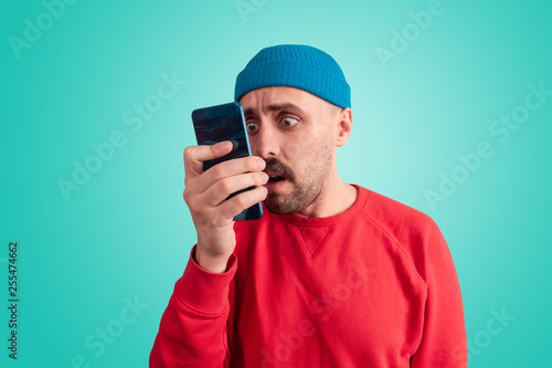 Astonished man looking at phone screen very closely