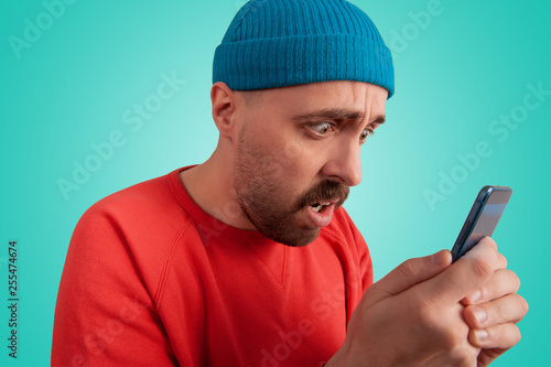 Panicked emotional male hipster using cell phone © serguastock