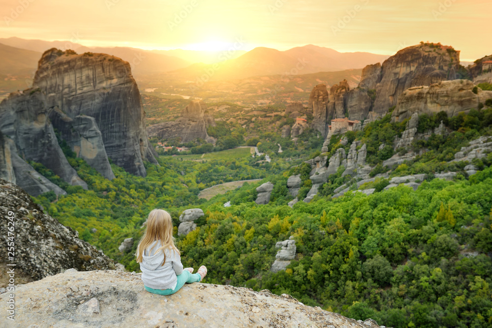 Child exploring Meteora valley, a rock formation in central Greece hosting one of the largest complexes of Eastern Orthodox monasteries, built on immense natural pillars.