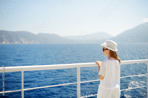 Adorable young girl enjoying ferry ride staring at the deep blue sea. Child having fun on summer family vacation in Greece.