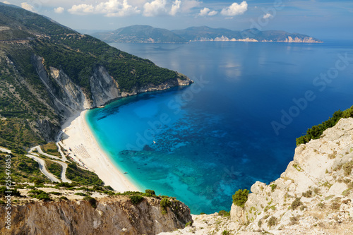 Aerial view of Myrtos beach, the most famous and beautiful beach of Kefalonia, a large coast with turqoise water and white coarse sand, surrounded by steep cliffs.