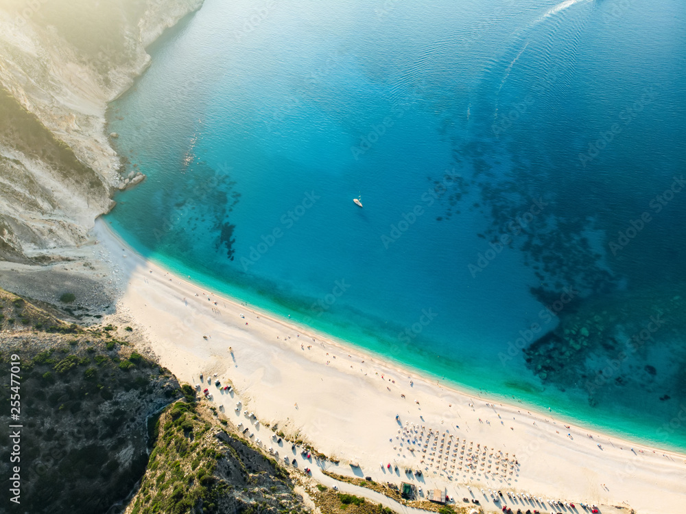 Aerial top down view of Myrtos beach, the most famous and beautiful beach of Kefalonia, a large coast with turqoise water and white coarse sand, surrounded by steep cliffs.
