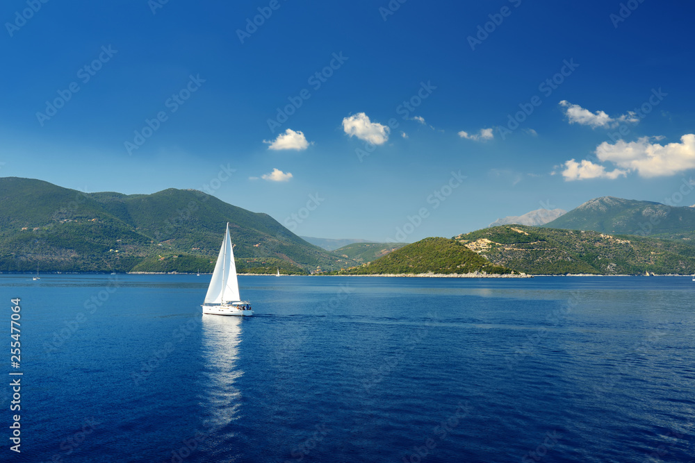 Obraz premium Scenic view of Nidri port with boats and yachts passing by. Coast of Lefkada island on sunny summer day.