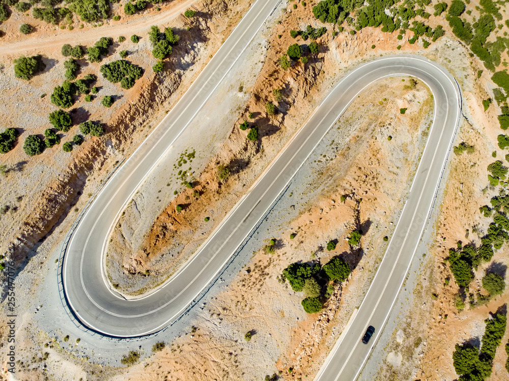 Aerial view of serpentine road snaking between mountains in West Greece. A road full of twists and turns winding sharply up the mountain in Peloponnese region, Greece.