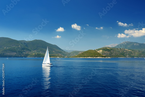Scenic view of Nidri port with boats and yachts passing by. Coast of Lefkada island on sunny summer day.