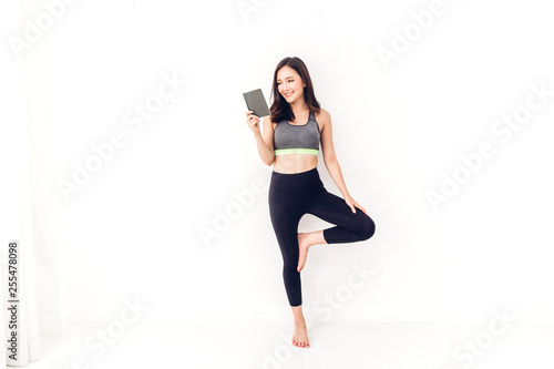 Sport woman in sportswear relax reading a book after workout against copy space for adding text with white wall background.Diet concept.Fitness and healthy lifestyle