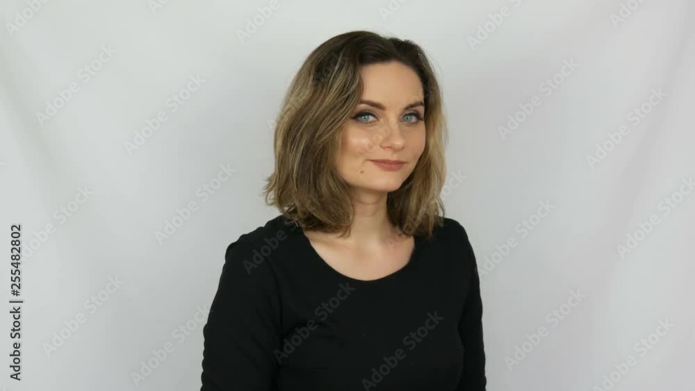 Beautiful young sexy woman in black dress approvingly with love gently and smilingly looking into the camera on a white background in the studio Beautiful young sexy woman in black dress approvingly with love gently and smilingly looking into the camera on a white background in the studio