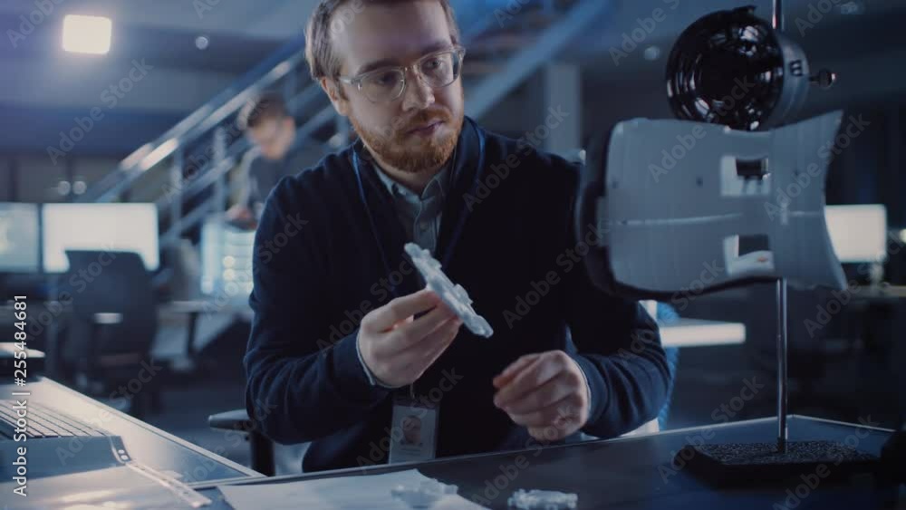 Electronics Development Engineer Working at His Desk, Fits Component into Prototype. Professionals Work in the Advanced Technology Designing Agency. Modern Research Centre Using 3D Printing Electronics Development Engineer Working at His Desk, Fits Component into Prototype. Professionals Work in the Advanced Technology Designing Agency. Modern Research Centre Using 3D Printing