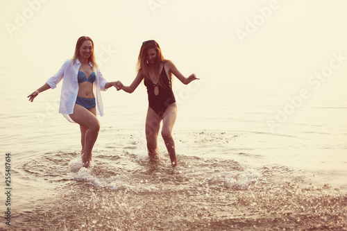 Two girls having fun in the sea at sunset.
