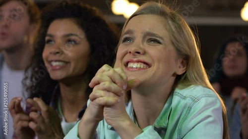 Female fans emotionally cheering for sports team victory watching football match