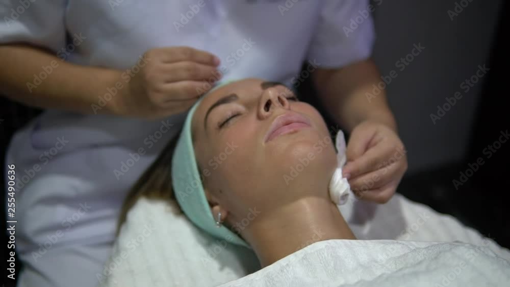 girl client in the beauty salon enjoying spa treatments, they clean her face girl client in the beauty salon enjoying spa treatments, they clean her face