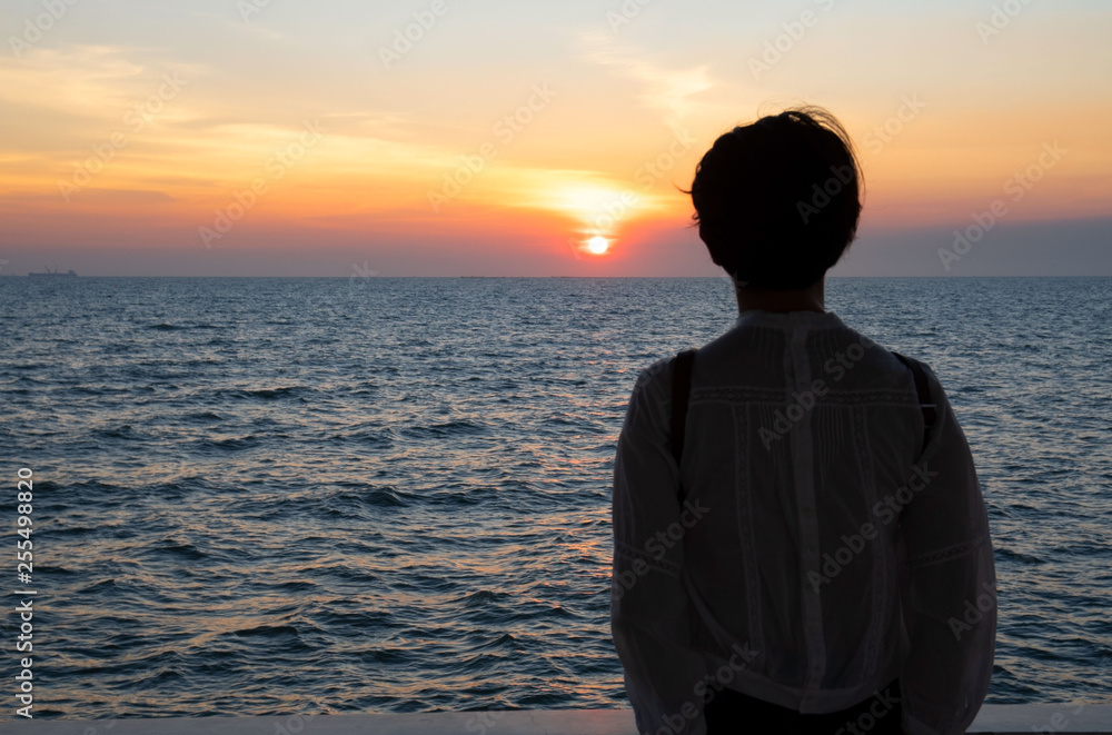 Silhouette rear view of young woman standing near the sea and sky Twilight background for amazing landscape Happy freedom for success and bliss concept. Silhouette rear view of young woman standing near the sea and sky Twilight background for amazing landscape Happy freedom for success and bliss concept.