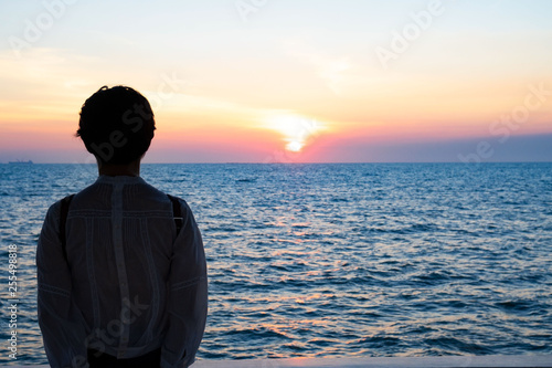 Silhouette rear view of young woman standing near the sea and sky Twilight background for amazing landscape Happy freedom for success and bliss concept.