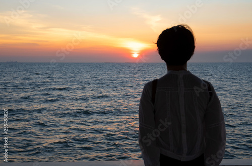 Silhouette rear view of young woman standing near the sea and sky Twilight background for amazing landscape Happy freedom for success and bliss concept.