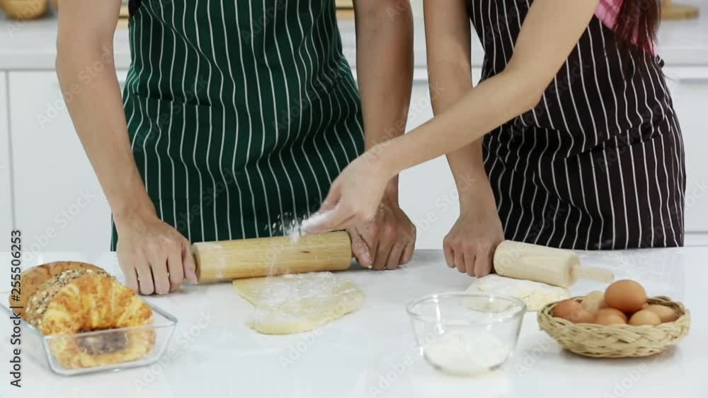 Slow motion scene video of two people in kitchen, one of them scatters the flour on the dough for made bakery. Slow motion scene video of two people in kitchen, one of them scatters the flour on the dough for made bakery.