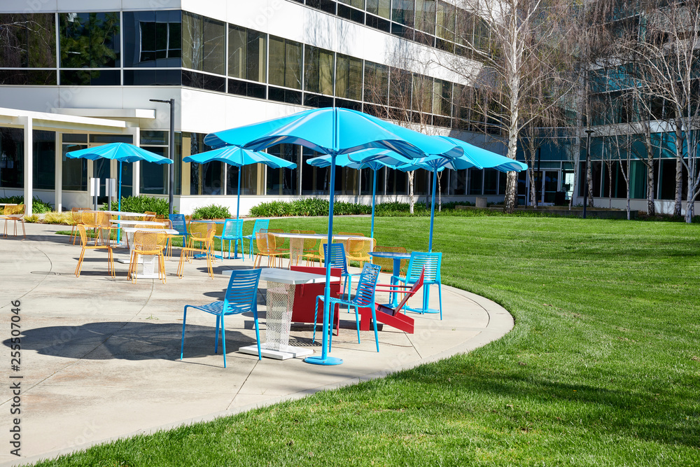 blue and yellow chairs under blue umbrellas in a corporate office park