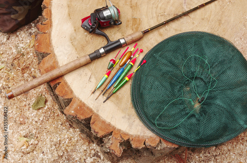 Rod with reel, fishing pond and floats on a tree stump