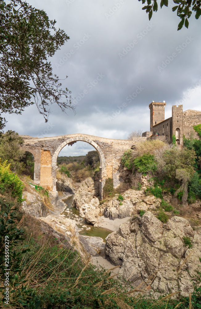 Fototapeta premium Vulci (Italy) - The medieval castle of Vulci, now museum, with Devil's bridge. Vulci is an etruscan ruins city in Lazio region, on the Fiora river between Montalto di Castro and Canino.