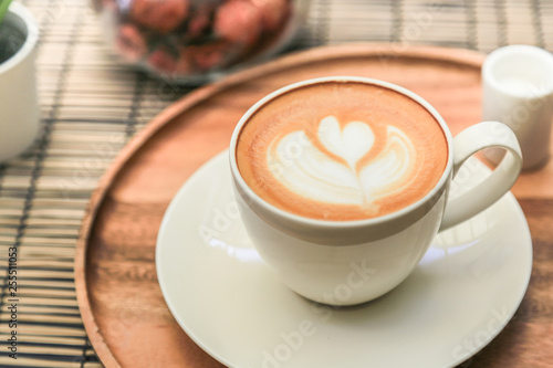 Hot latte coffee on a wooden tray with warm light