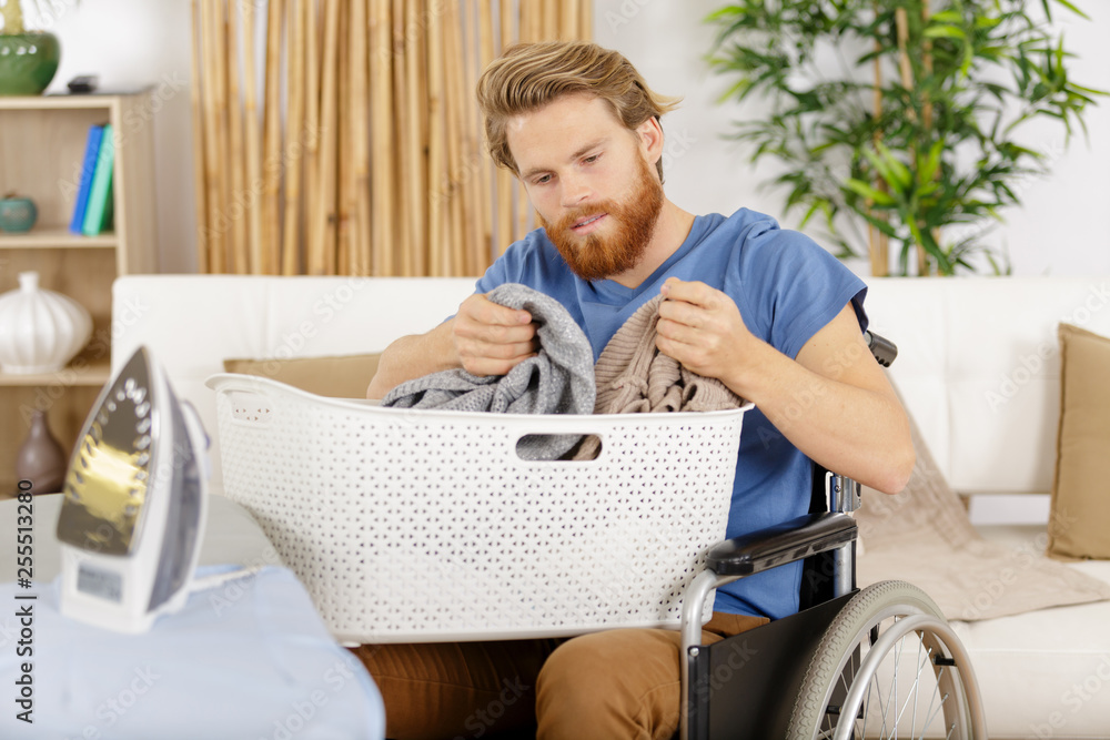 happy man on wheelchair dealing with laundry basket