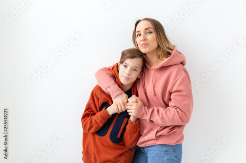 Mothers day, children and family concept - teen boy hugging his mom on white background