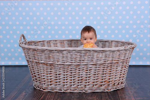 A tiny child eats a dry bun in a basket woven from a wicker tree.