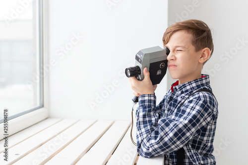 photographer, children and hobby concept - cute teen boy posing with retro camera on white background