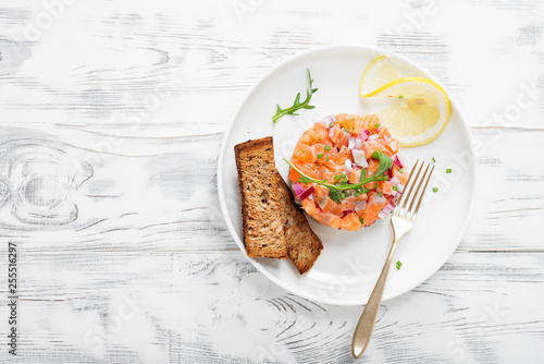 Foto Salmon tartare with red onion, avocado, arugula and bread toast.